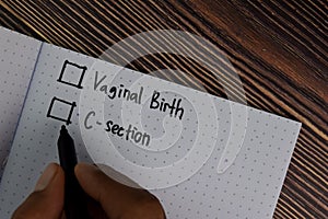 Vaginal Birth and C-section write on a book. Supported by an additional services isolated wooden table