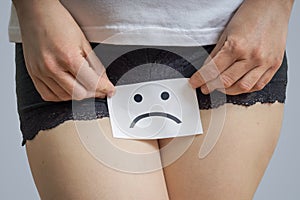 Vaginal or menstrual problems concept. Young woman holds paper with SOS above crotch. photo