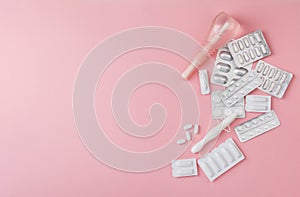 Vaginal suppositories, enema, tablets, applicator sanitary napkin on pink background