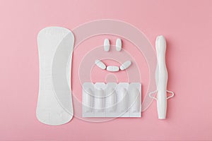 Vaginal suppositories, tablets, applicator and sanitary napkin on pink background