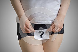 Vaginal or urinary infection and problems concept. Young woman holds paper with questionmark above crotch photo