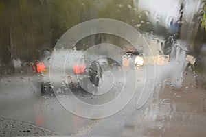 The vague image of the car through the glass which is filled in with a rain