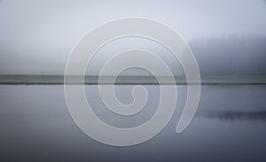 Vague misty and mysterious landscape with channel and grass river bank