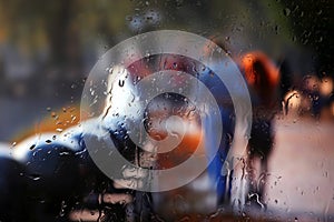 Vague silhouette of two people through rainy glass