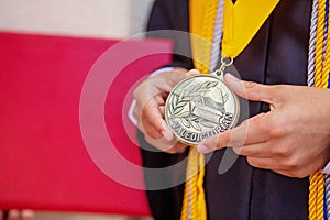 Valedictorian Shows off Medal with Graduation Gown photo