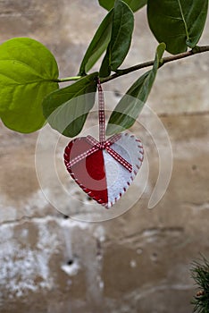 Valentine background with a sewed pillow remand white heart row border on red rope hanging on green leaves.
