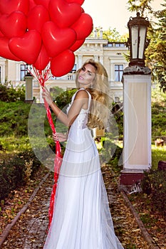 Valentine Beautiful girl with red balloons laugh, in the park. Beautiful happy young woman. Birthday party and bride at the