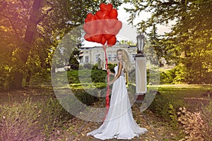 Valentine Beautiful girl with red balloons laugh, in the park. Beautiful happy young woman. Birthday party and bride at the