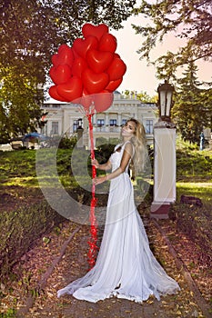 Valentine Beautiful girl with red balloons laugh, in the park. Beautiful happy young woman. Birthday party and bride at the