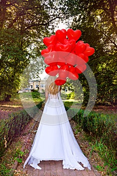 Valentine Beautiful girl with red balloons laugh, in the park. Beautiful happy young woman. Birthday party and bride at the