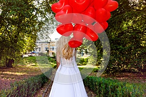 Valentine Beautiful girl with red balloons laugh, in the park. Beautiful happy young woman. Birthday party and bride at the