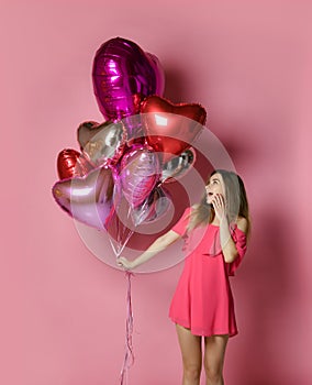Valentine Beauty girl hold red and pink air balloons laughing on pink background celebrating Valentines Day