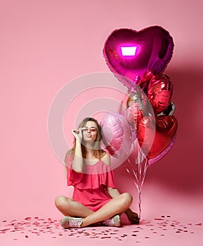 Valentine Beauty girl hold red and pink air balloons laughing on pink background celebrating Valentines Day