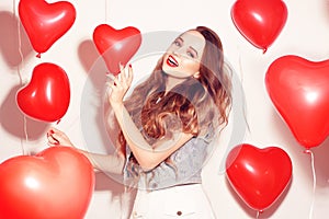 Valentine Beauty girl with red air balloons laughing, on white background. Beautiful Happy Young woman. Womans day. Holiday party.