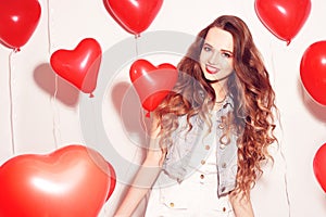 Valentine Beauty girl with red air balloons laughing, on white background. Beautiful Happy Young woman. Womans day. Holiday party.