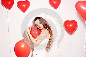 Valentine Beauty girl with red air balloons laughing, on white background. Beautiful Happy Young woman. Womans day. Holiday party