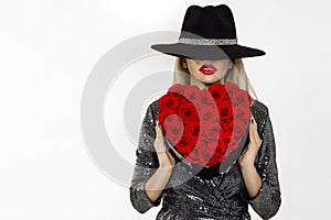 Valentine Beauty girl with red heart roses. Portrait of a young female model with gift and hat, isolated on background.