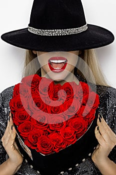 Valentine Beauty girl with red heart roses. Portrait of a young female model with gift and hat, isolated on background.