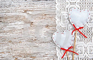 Valentine card with textile hearts on lacy cloth and old wood