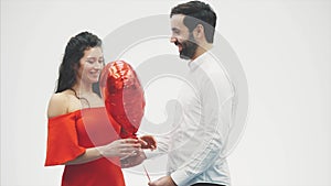 Valentine Couple. Beauty Girl and her Handsome Boyfriend holding heart shaped air balloon and kissing. Happy Joyful