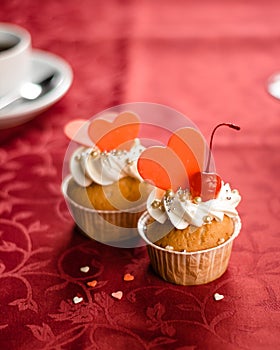 Valentine cupcakes decorated with sweet hearts on wooden table on a red background