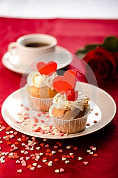 Valentine cupcakes decorated with sweet hearts on wooden table on a red background