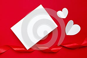 Valentine Day card mockup with white hearts and ribbon on red background, top view, flat lay. Blank invitation, flyer, greeting