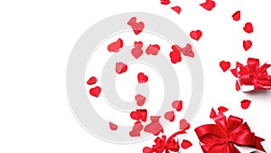 Valentine day composition. gift box with a big red bow on a white background strewn with hearts with copy space. Top View