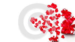 Valentine day composition. gift box with a big red bow on a white background strewn with hearts with copy space. Top View