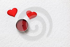 Valentine day concept. Two red hearts and candle on white snow