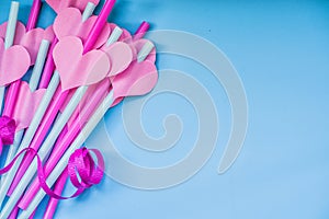 Valentine day holiday. bright pink and blue drinking straws with hearts and a pink ribbon on blue.bright sipping straws for par