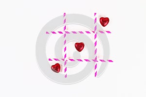 Valentine day layout. Noughts and crosses pink straws and hearts on a white background. Tic tac toe. St. Valentines Day, day love