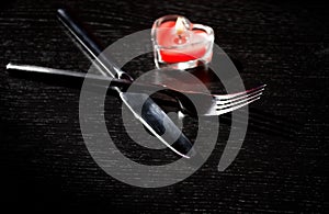 Valentine day table setting with knife, fork, red burning heart shaped candle