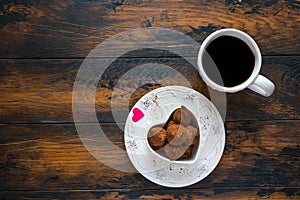 Valentine day, white vintage plate, sweets and heart made from red paper, cup of black coffee.