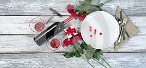 Valentine dinner with wine and roses on rustic wooden table