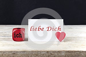 Valentine greeting card on wooden table with text Ich liebe Dich, written in German, which means I love you.
