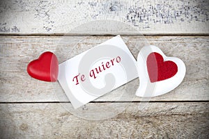 Valentine greeting card on wooden table with text written in spanish Te quiero, which means I love you photo