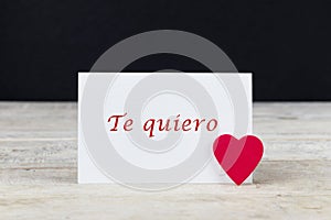 Valentine greeting card on wooden table with text written in spanish Te quiero, which means I love you photo