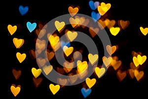 Valentine grunge heart shaped lights background. Yellow gold and blue heart-shaped on black background