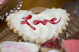 Valentine heart cookie with the word Love written in red frosting on a white frosting.