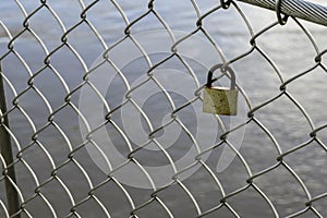 Valentine heart padlock attached to wire mesh fence. Love padlocks hanging on a bridge