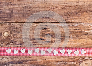 Valentine hearts decoration on red ribbon border and rustic wood background