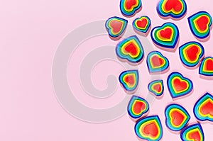 Valentine lgbt festive background - rainbow bright hearts as decorative border on pastel pink backdrop, top view.
