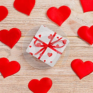 Valentine or other holiday handmade present in paper with red hearts and gifts box in holiday wrapper. Present box of gift on