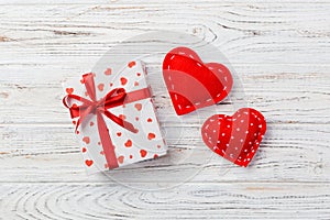 Valentine or other holiday handmade present in paper with red hearts and gifts box in holiday wrapper. Present box of gift on