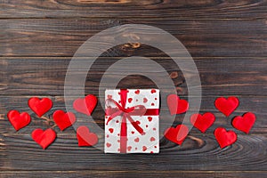 Valentine or other holiday handmade present in paper with red hearts and gifts box in holiday wrapper. Present box of gift on Dark