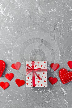 Valentine or other holiday handmade present in paper with red hearts and gifts box in holiday wrapper. Present box of gift on grey