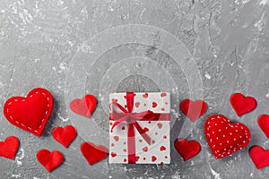 Valentine or other holiday handmade present in paper with red hearts and gifts box in holiday wrapper. Present box of gift on grey