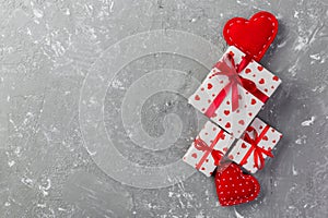 Valentine or other holiday handmade present in paper with red hearts and gifts box in holiday wrapper. Present box of gift on grey