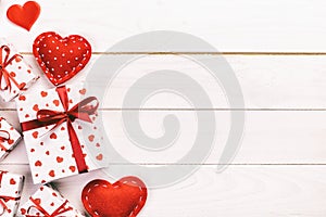 Valentine or other holiday handmade present in paper with red hearts and gifts box in holiday wrapper. Present box gift on wooden